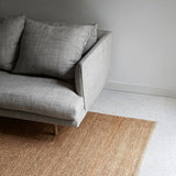 Nest Rug by Armadillo, handwoven from 100% natural jute with neatly finished ends, available in Natural and Charcoal tones, offering a minimalist design that adds warmth and texture to living spaces.