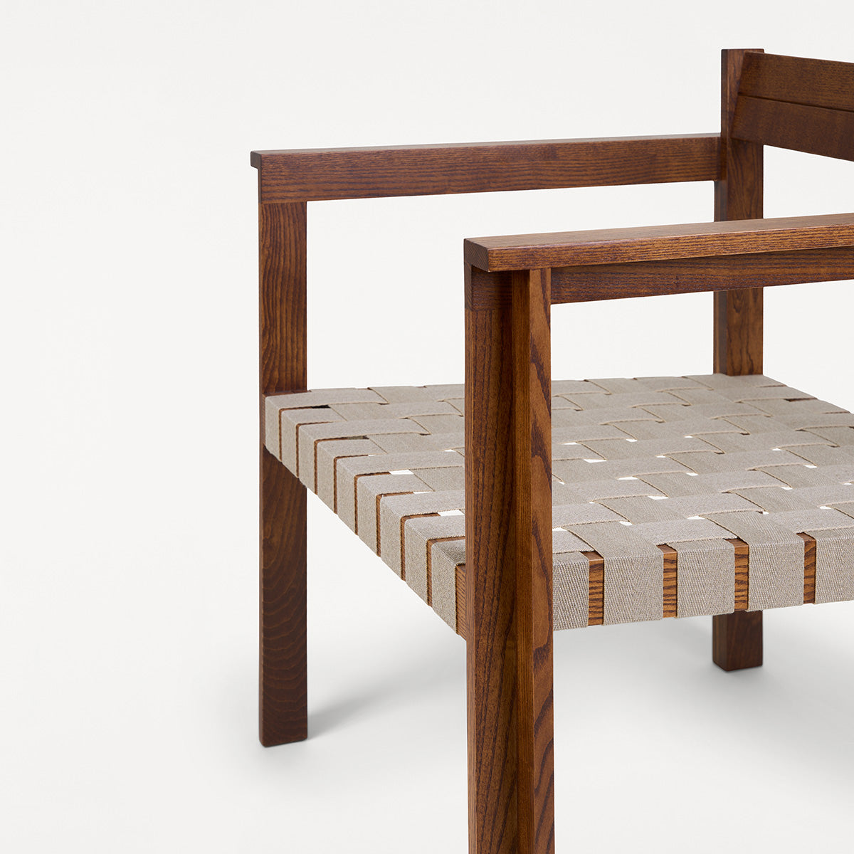Symmetry lounge chair made from natural oiled ash wood with a comfortable seat in light linen-blend fabric, featuring an open, minimalist frame and Scandinavian aesthetic