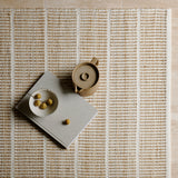Trellis Rug by Armadillo, handwoven from a blend of wool and jute, featuring uniform stripes in color combinations such as Natural & White, Natural & Bison, and Natural & Sandstone, offering a contemporary take on traditional Moroccan Tuareg designs.