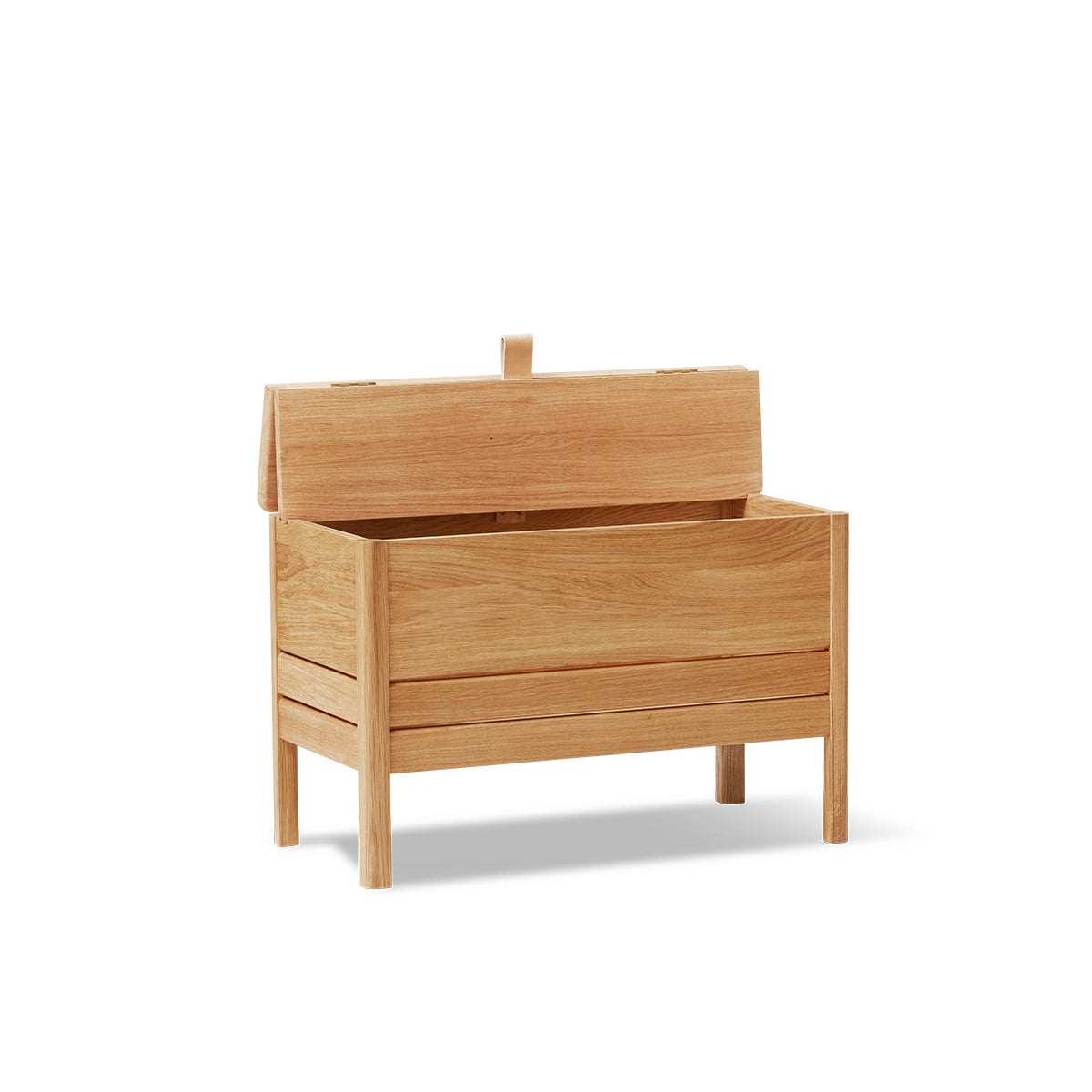 A Line Storage Bench by Form & Refine, crafted from solid European oak with a minimalist design, featuring a leather handle and two spacious compartments for organized storage, available in oak, white oak, and black finishes.