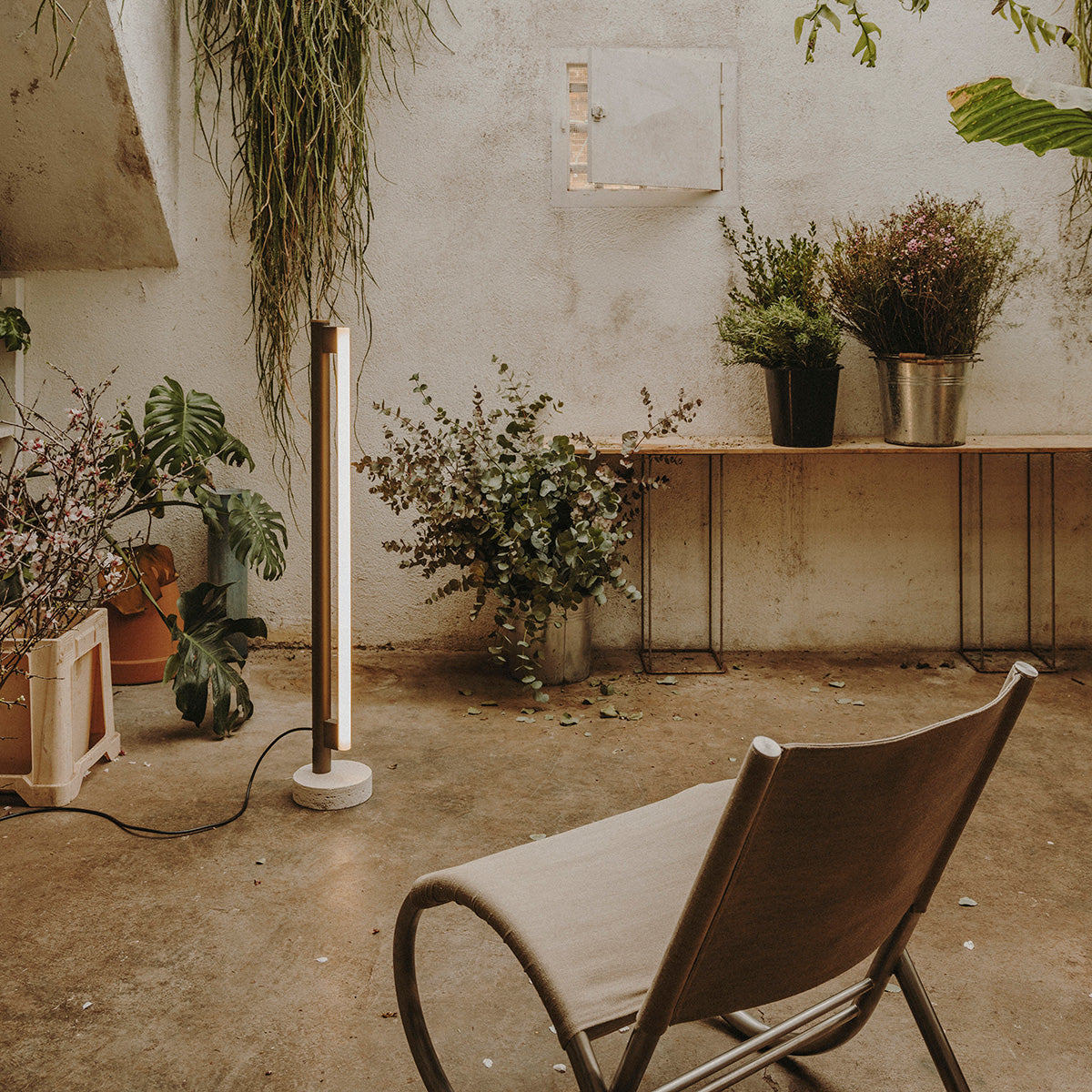 Eiffel Vloerlamp van Frama met een minimalistisch ontwerp, roestvrijstalen frame, opaalglazen LED-buis en een natuurstenen voet, biedt dimbaar sfeerverlichting geschikt voor diverse interieurinstellingen.