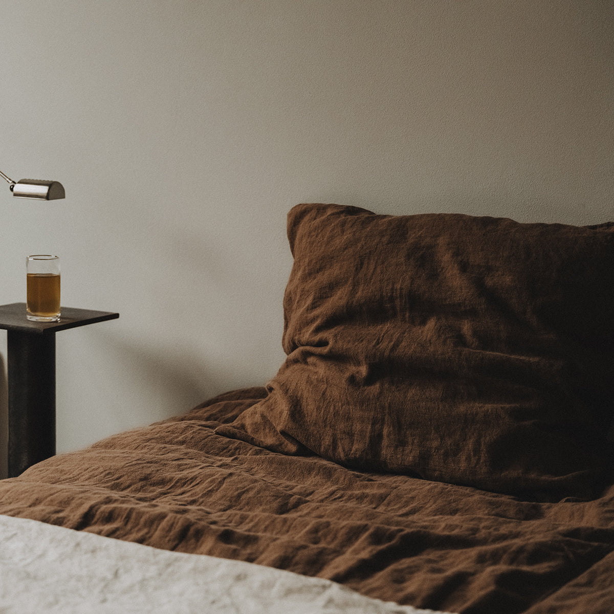 By Mölle's cocoa linen duvet cover, crafted from 100% pre-washed European flax linen, features a warm, deep brown shade. The breathable and hypoallergenic fabric provides comfort year-round and is available with either wooden buttons or a tuck-in flap closure.