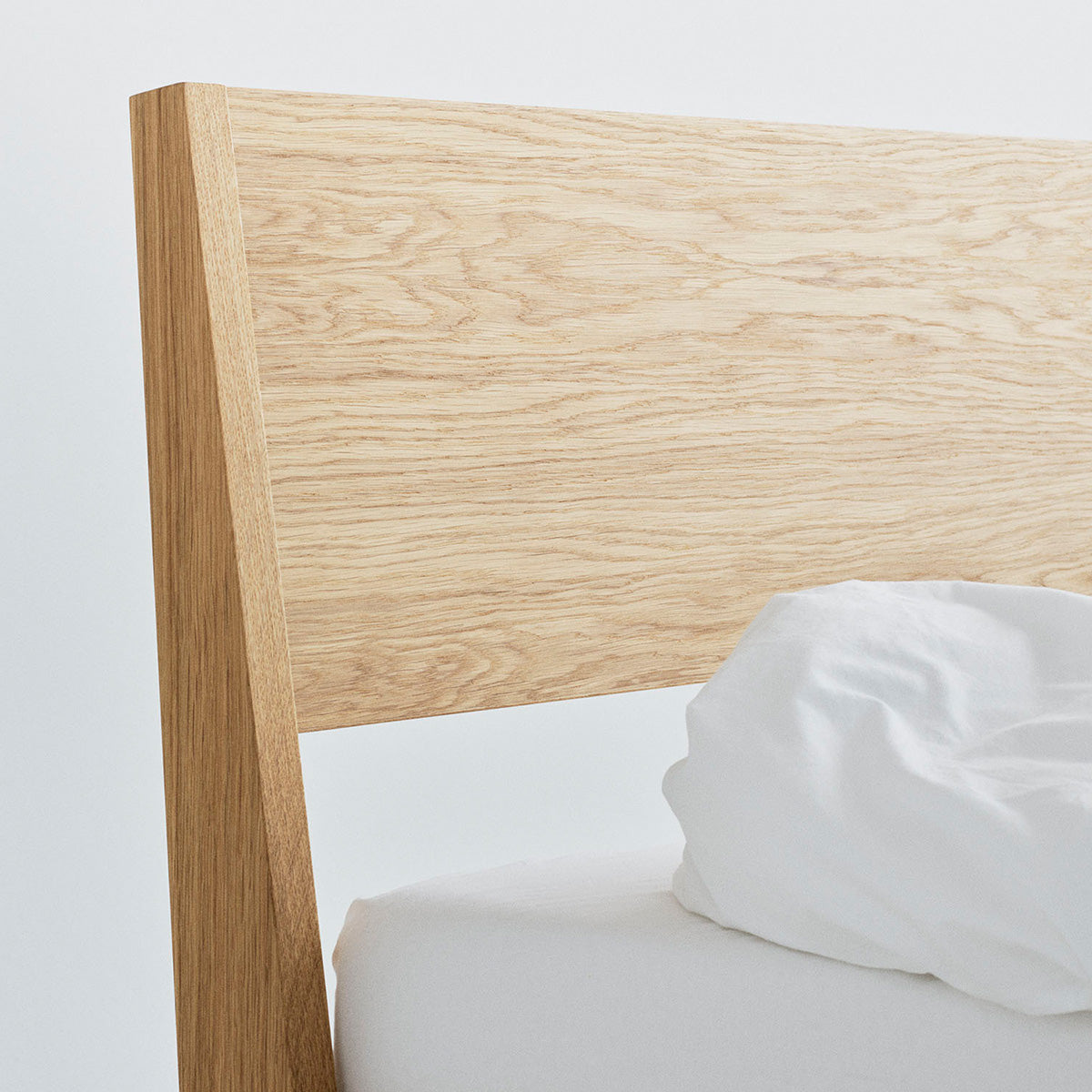 Ejer Bed Frame by RYE available in oiled oak, black stained oak, or smoked oak finishes, featuring a minimalist design with clean lines and a slightly inclined headboard, crafted for a tranquil and restful sleep environment