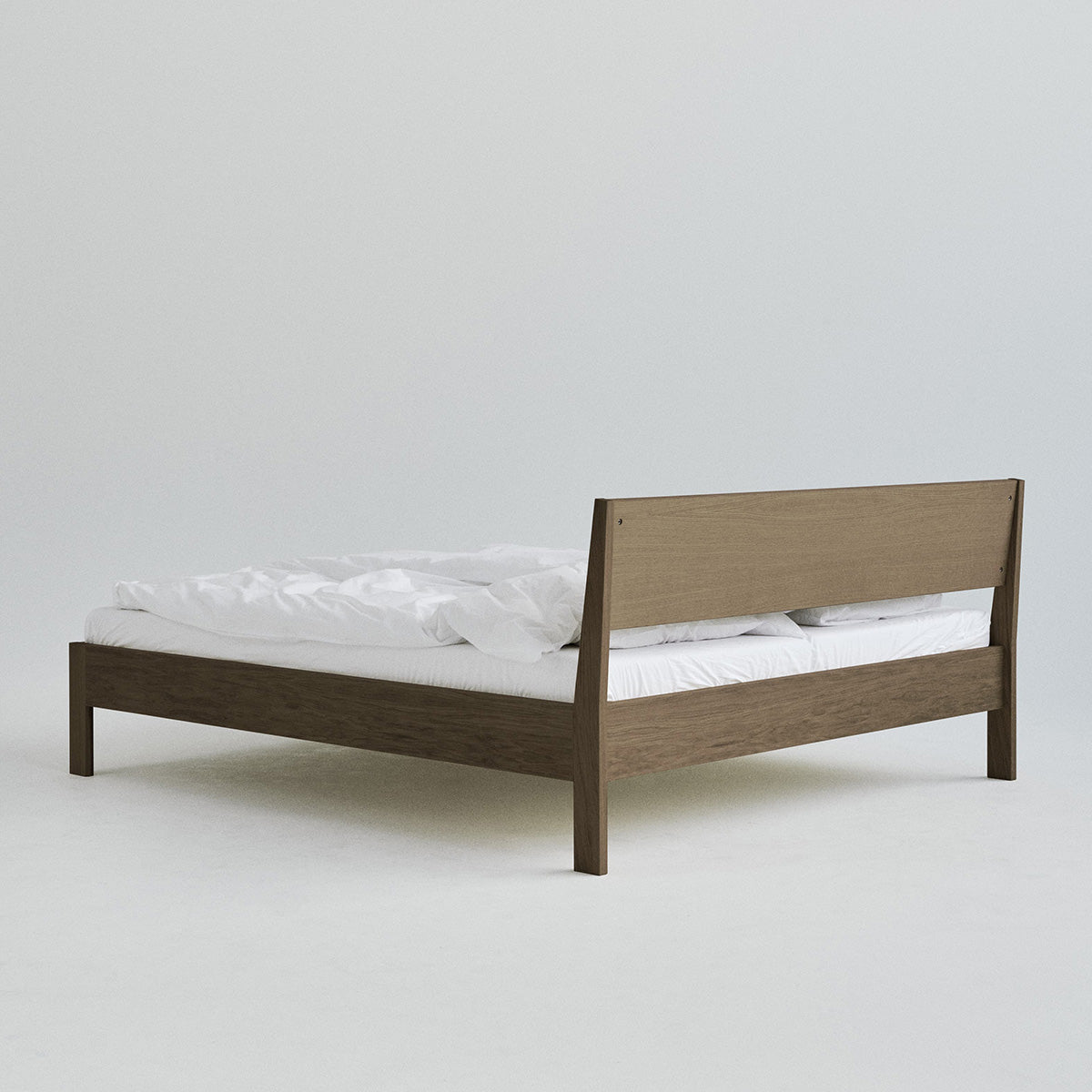 Ejer Bed Frame van RYE beschikbaar in geolied eiken, zwart gebeitst eiken of gerookt eiken, met een minimalistisch ontwerp, strakke lijnen en een licht hellend hoofdeinde, ontworpen voor een rustige en rustgevende slaapomgeving.