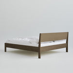 Ejer Bed Frame van RYE beschikbaar in geolied eiken, zwart gebeitst eiken of gerookt eiken, met een minimalistisch ontwerp, strakke lijnen en een licht hellend hoofdeinde, ontworpen voor een rustige en rustgevende slaapomgeving.
