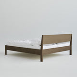 Ejer Bed Frame van RYE beschikbaar in geolied eiken, zwart gebeitst eiken of gerookt eiken, met een minimalistisch ontwerp, strakke lijnen en een licht hellend hoofdeinde, ontworpen voor een rustige en rustgevende slaapomgeving.