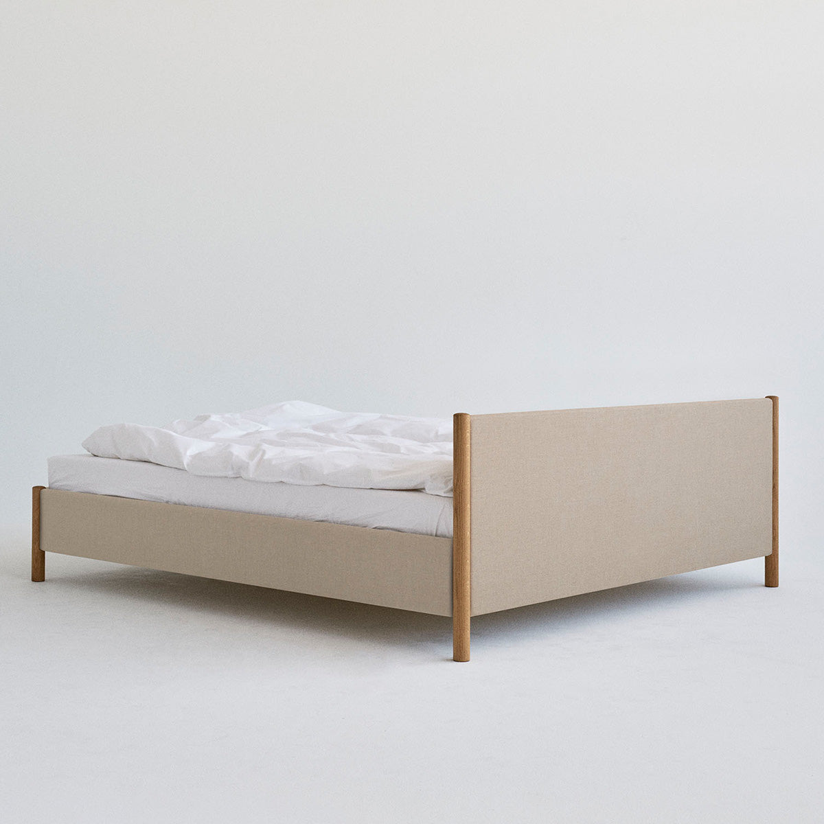 Veng Bed Frame van RYE met een minimalistisch ontwerp, voorzien van een met linnen beklede frame en massief eikenhouten poten, die Scandinavisch vakmanschap en tijdloze elegantie belichamen.