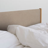 Veng Bed Frame by RYE featuring a minimalist design with a linen-upholstered frame and solid oak wood posts, embodying Scandinavian craftsmanship and timeless elegance.