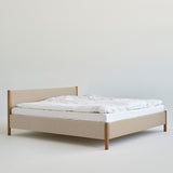 Veng Bed Frame by RYE featuring a minimalist design with a linen-upholstered frame and solid oak wood posts, embodying Scandinavian craftsmanship and timeless elegance.