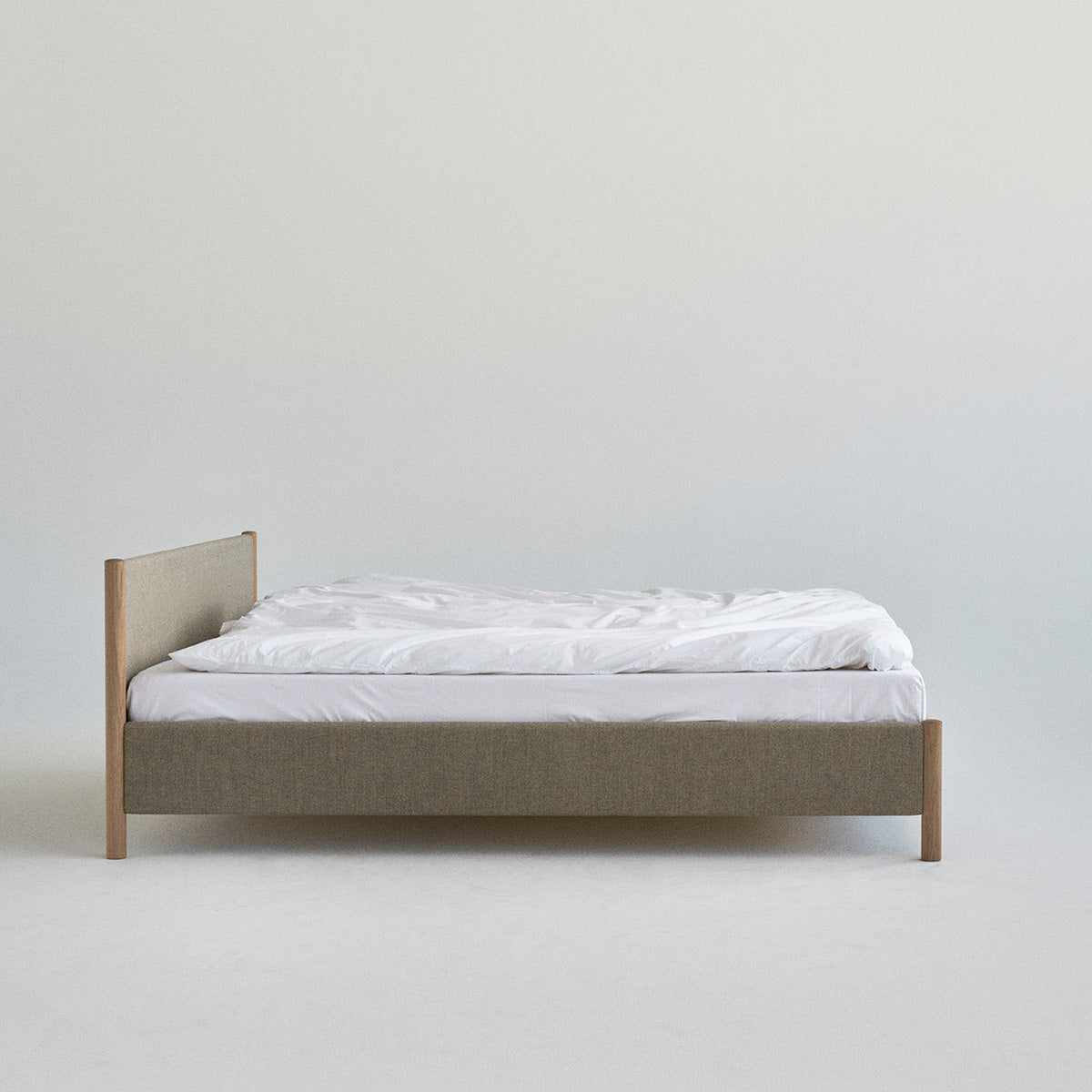 Minimalistisch houten bedframe, ontworpen door Rye Sleep en verkrijgbaar bij By Mölle. Met strakke Scandinavische lijnen, een laag silhouet en een zacht gestoffeerd hoofdbord combineert dit bed tijdloos design met natuurlijke materialen voor een rustige, moderne slaapkamer.
