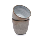 Hand-thrown ceramic cup in soft grey tones with a matte interior and minimal rounded shape