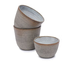 Zijaanzicht van de grijze handgemaakte kop — zichtbaar de zachte structuur, afgeronde lip en natuurlijke kleurverschillen door handwerk