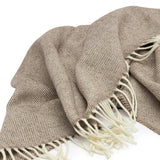 Lambswool Throw in Cocoa by By Mölle – 100% Merino lambswool woven in a classic herringbone pattern, combining natural cream and warm brown shades. Measuring 140 x 200 cm, this lightweight yet warm throw is crafted in Europe and machine washable on a wool program. Ideal for adding a cozy touch to your living space.