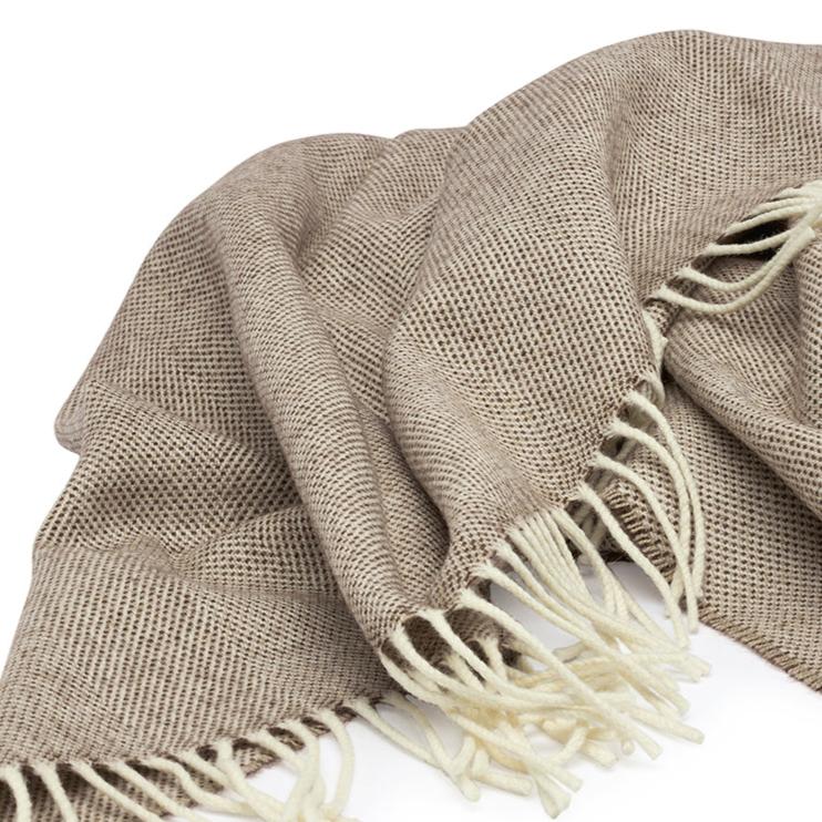Lambswool Throw in Cocoa by By Mölle – 100% Merino lambswool woven in a classic herringbone pattern, combining natural cream and warm brown shades. Measuring 140 x 200 cm, this lightweight yet warm throw is crafted in Europe and machine washable on a wool program. Ideal for adding a cozy touch to your living space.