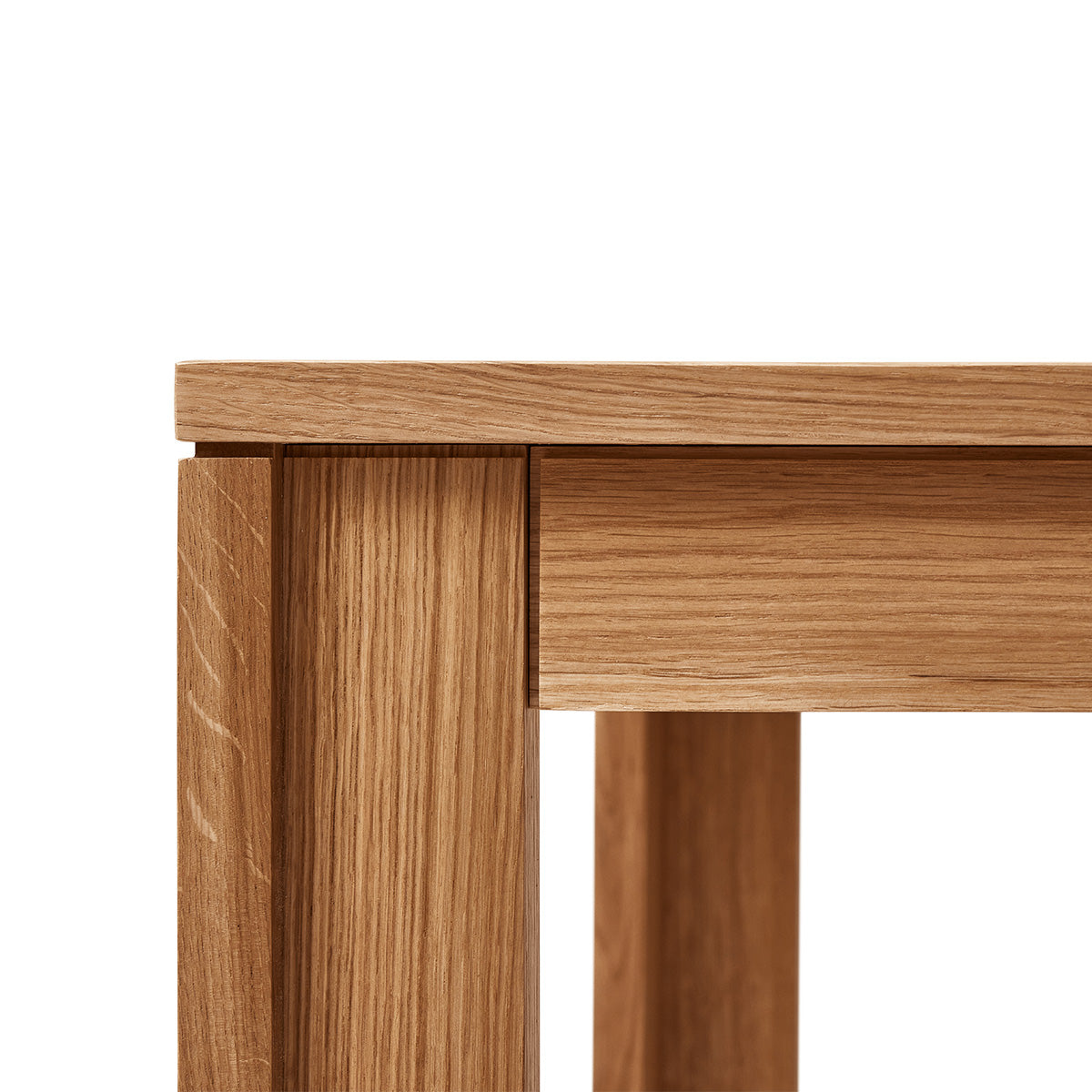 Vierkante tafel met ultra-dun tafelblad en verzonken poten van massief eikenhout. Subtiele schaduwlijn tussen blad en frame zorgt voor een licht zwevend effect. Modulair ontwerp dat meerdere tafels naadloos in een rij verbindt. Robuust en elegant, perfect voor dagelijks gebruik in moderne interieurs.