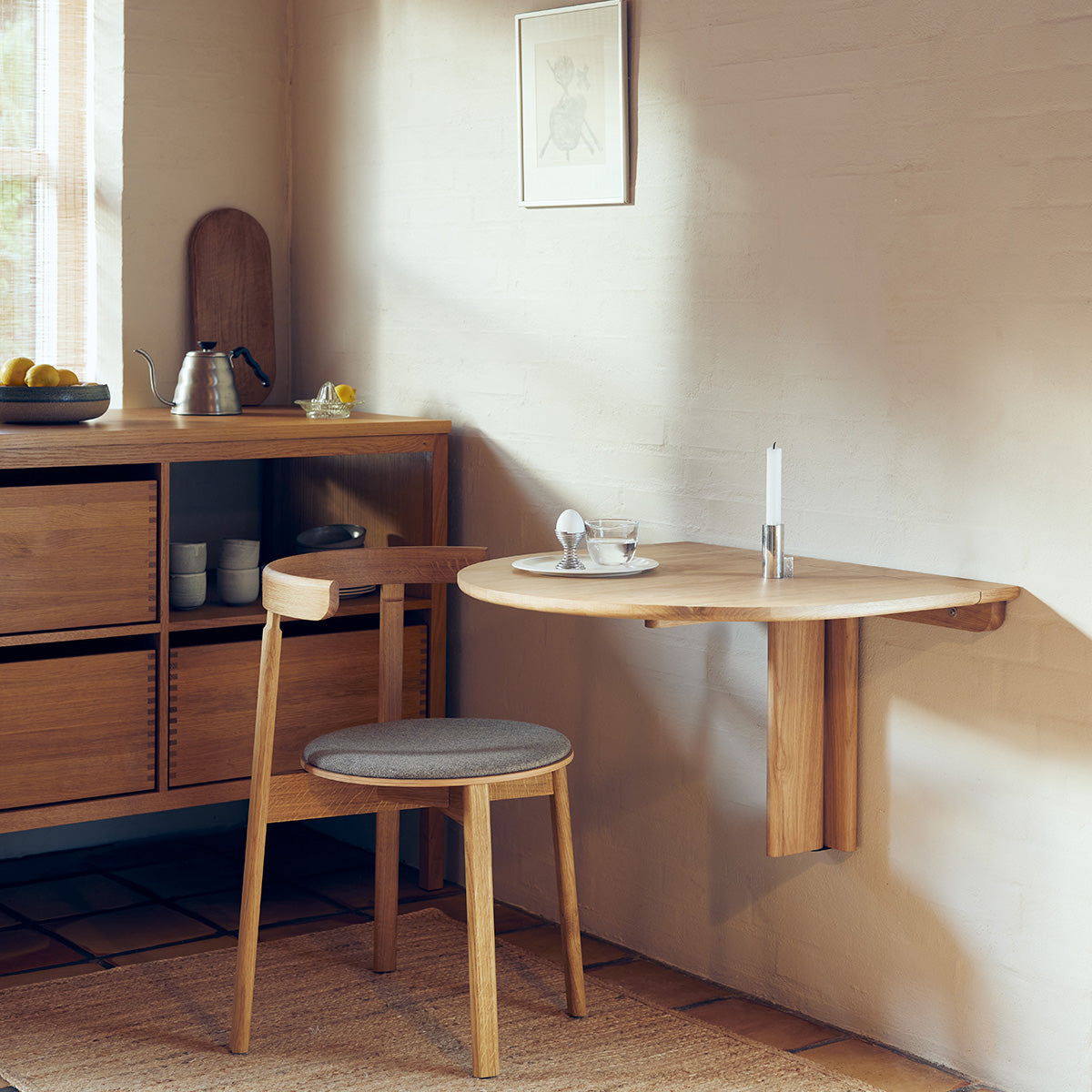 Minimalist folding wall table made of solid oak with a slender frame and concealed hinge mechanism. Oval tabletop folds away easily, ideal for small spaces.