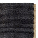 Nest Rug by Armadillo, handwoven from 100% natural jute with neatly finished ends, available in Natural and Charcoal tones, offering a minimalist design that adds warmth and texture to living spaces.