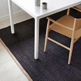 Nest vloerkleed van Armadillo, handgeweven van 100% natuurlijke jute met zorgvuldig afgewerkte uiteinden, verkrijgbaar in de kleuren Natural en Charcoal, biedt een minimalistisch ontwerp dat warmte en textuur toevoegt aan woonruimtes.