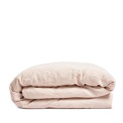 By Mölle's blush linen duvet cover, crafted from 100% pre-washed European flax linen, features a soft, powdery pink hue achieved through chambray weaving. This breathable and hypoallergenic fabric offers comfort year-round and is available with either wooden buttons or a full-width tuck-in flap closure.