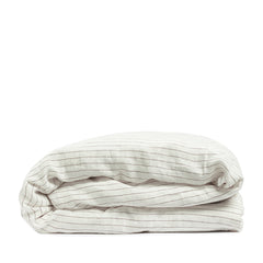 By Mölle's Cocoa Stripe linen duvet cover, crafted from 100% pre-washed European flax linen, features a warm white base with subtle cocoa-colored stripes. The chambray weave adds depth and character, offering a breathable and hypoallergenic fabric suitable for year-round comfort. Available with either wooden buttons or a full-width tuck-in flap closure.