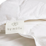 By Mölle's Recycled Down All Seasons Duvet Insert, crafted from 100% GOTS certified organic cotton and filled with 70% Dutch recycled down and 30% recycled feathers. This eco-friendly duvet features box stitching to ensure even distribution of the fill, providing consistent warmth throughout the night. The duvet is suitable for allergy sufferers, certified with the Nomite® label.