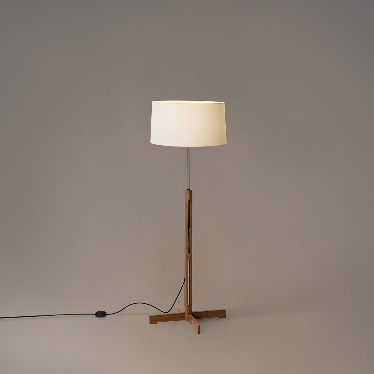Floor lamp with a wooden base and white shade on a plain background