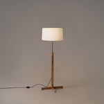 Floor lamp with a wooden base and white shade on a plain background