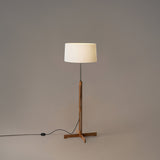 Floor lamp with a wooden base and white shade on a plain background