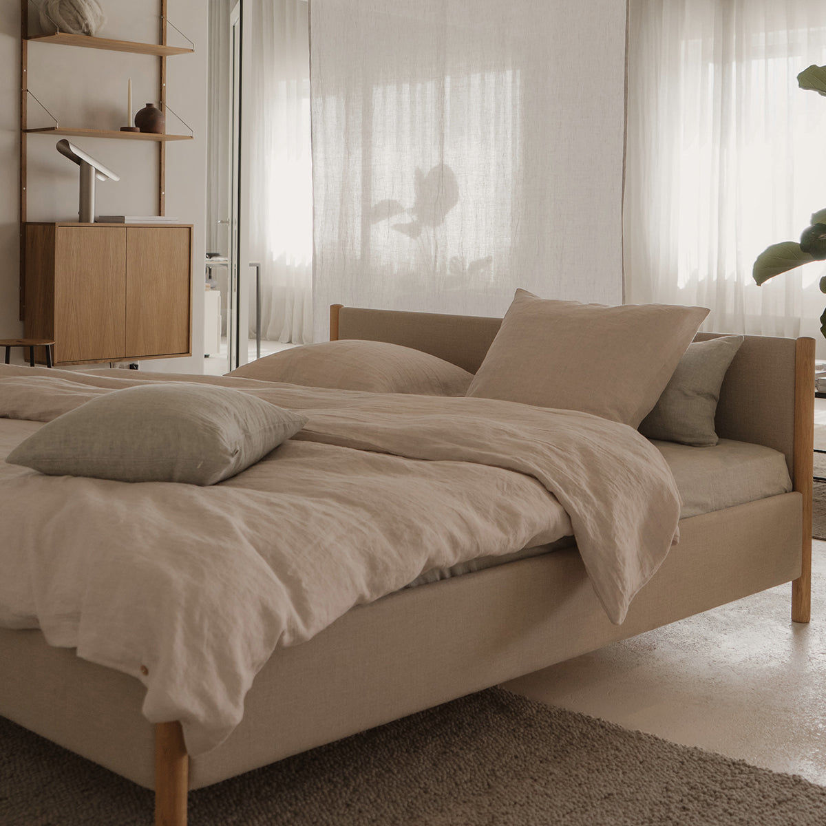 Minimalistisch houten bedframe, ontworpen door Rye Sleep en verkrijgbaar bij By Mölle. Met strakke Scandinavische lijnen, een laag silhouet en een zacht gestoffeerd hoofdbord combineert dit bed tijdloos design met natuurlijke materialen voor een rustige, moderne slaapkamer.