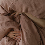 By Mölle's Pink Salt linen duvet cover, crafted from 100% pre-washed European flax linen, features a chambray weave combining pink and off-white threads. This warm pink hue adds a soft touch to any bedroom. The duvet cover is available with either wooden buttons or a tuck-in flap closure.