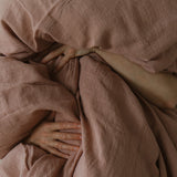 By Mölle's Pink Salt linen duvet cover, crafted from 100% pre-washed European flax linen, features a chambray weave combining pink and off-white threads. This warm pink hue adds a soft touch to any bedroom. The duvet cover is available with either wooden buttons or a tuck-in flap closure.