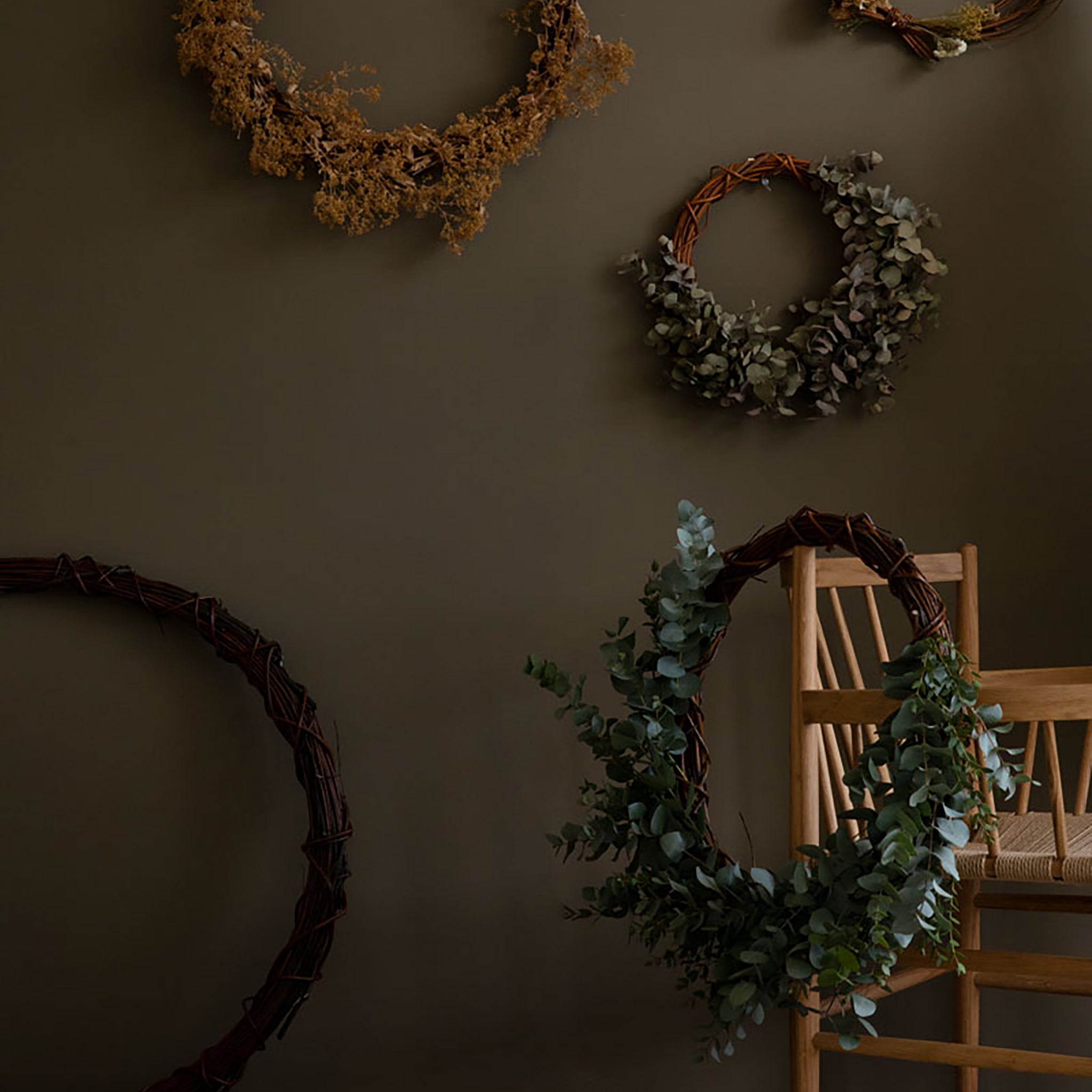 Wreaths on a wall with a chair and wooden surface in the foreground
