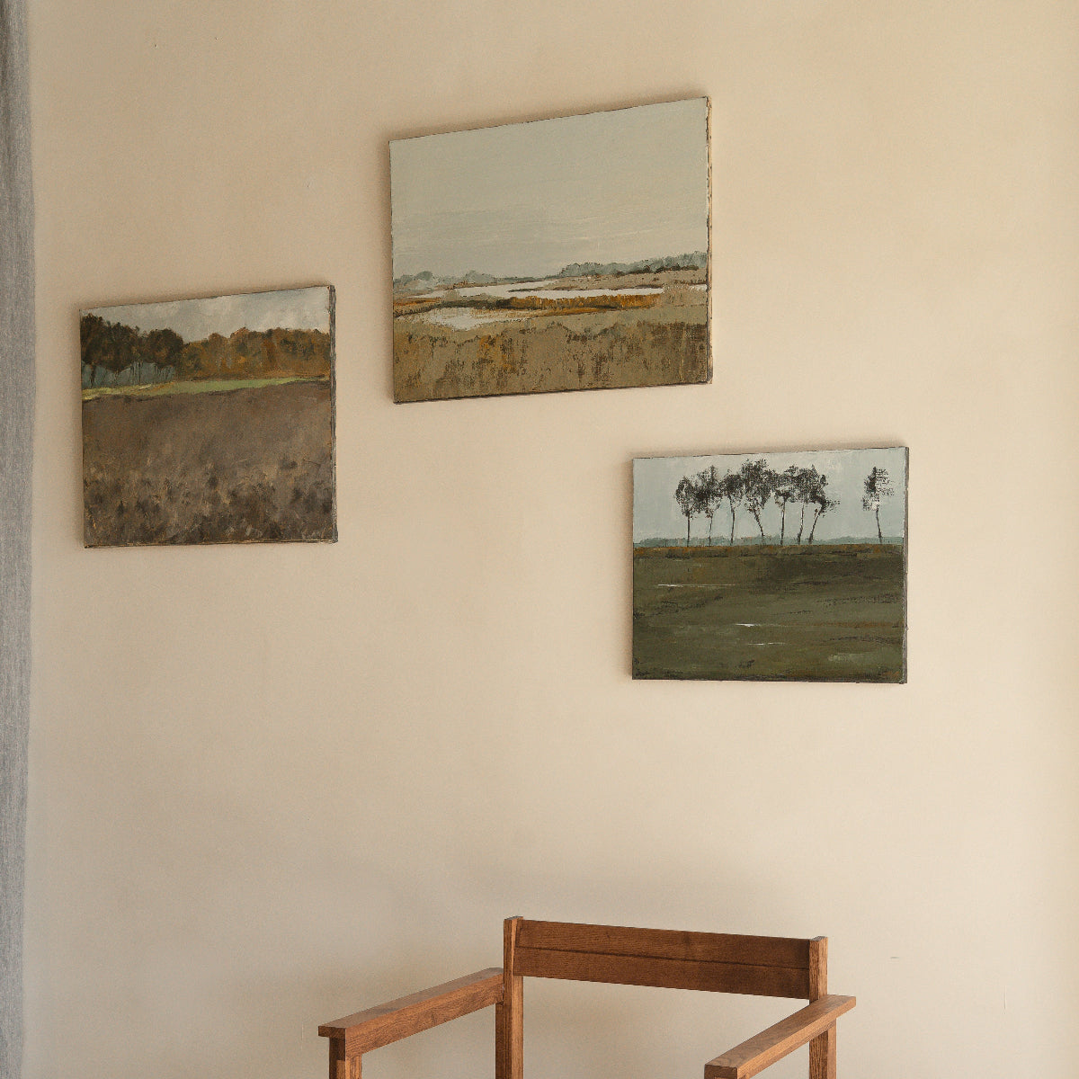 Wooden chair and stool with landscape paintings on a beige wall