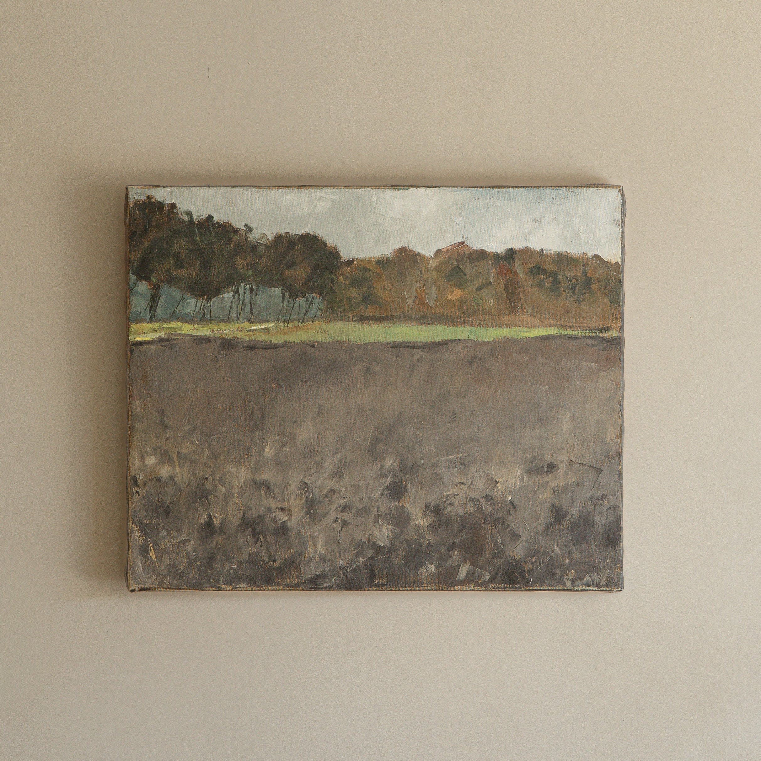Painting of a landscape with trees and water on a beige wall