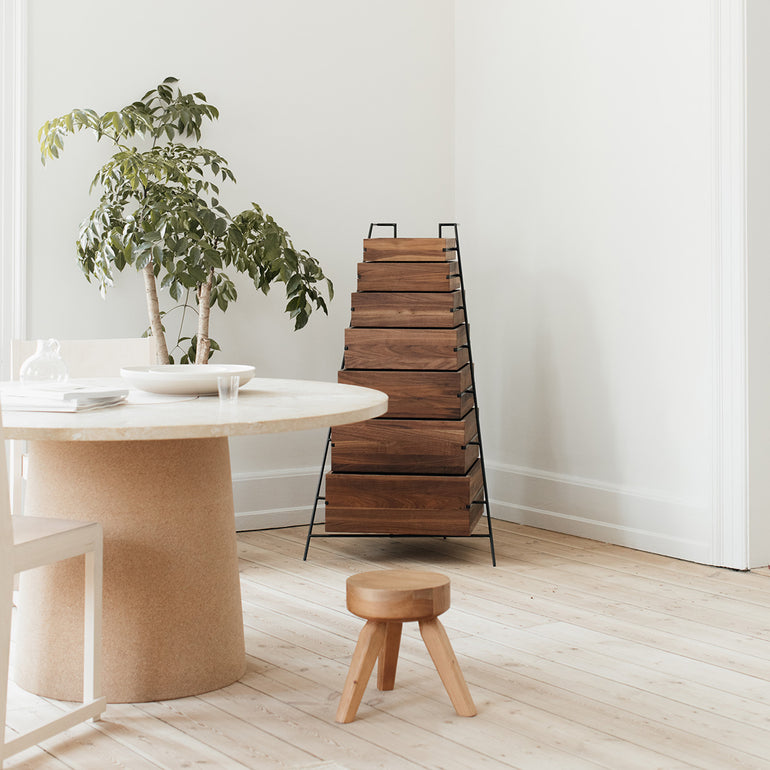 Frama AML stool pine in a dining room setting, with a round table and a storage rack