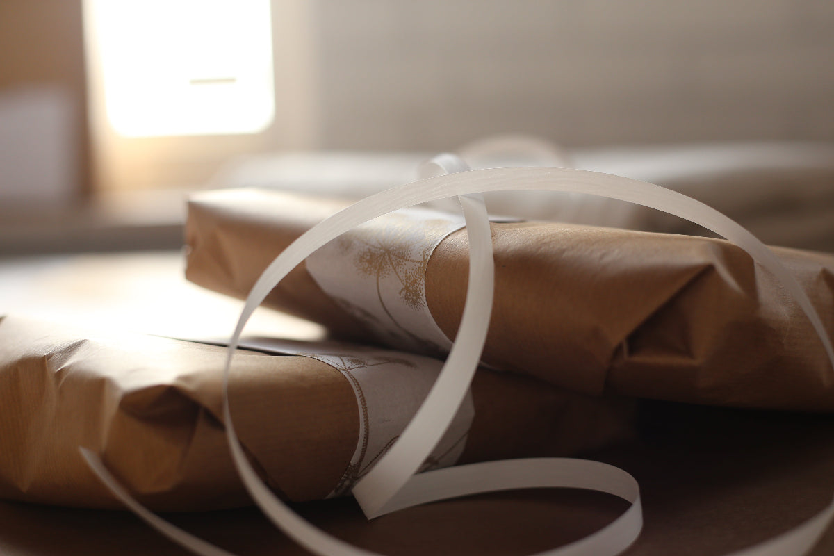Two packages wrapped in brown paper with white ribbons on a wooden surface.
