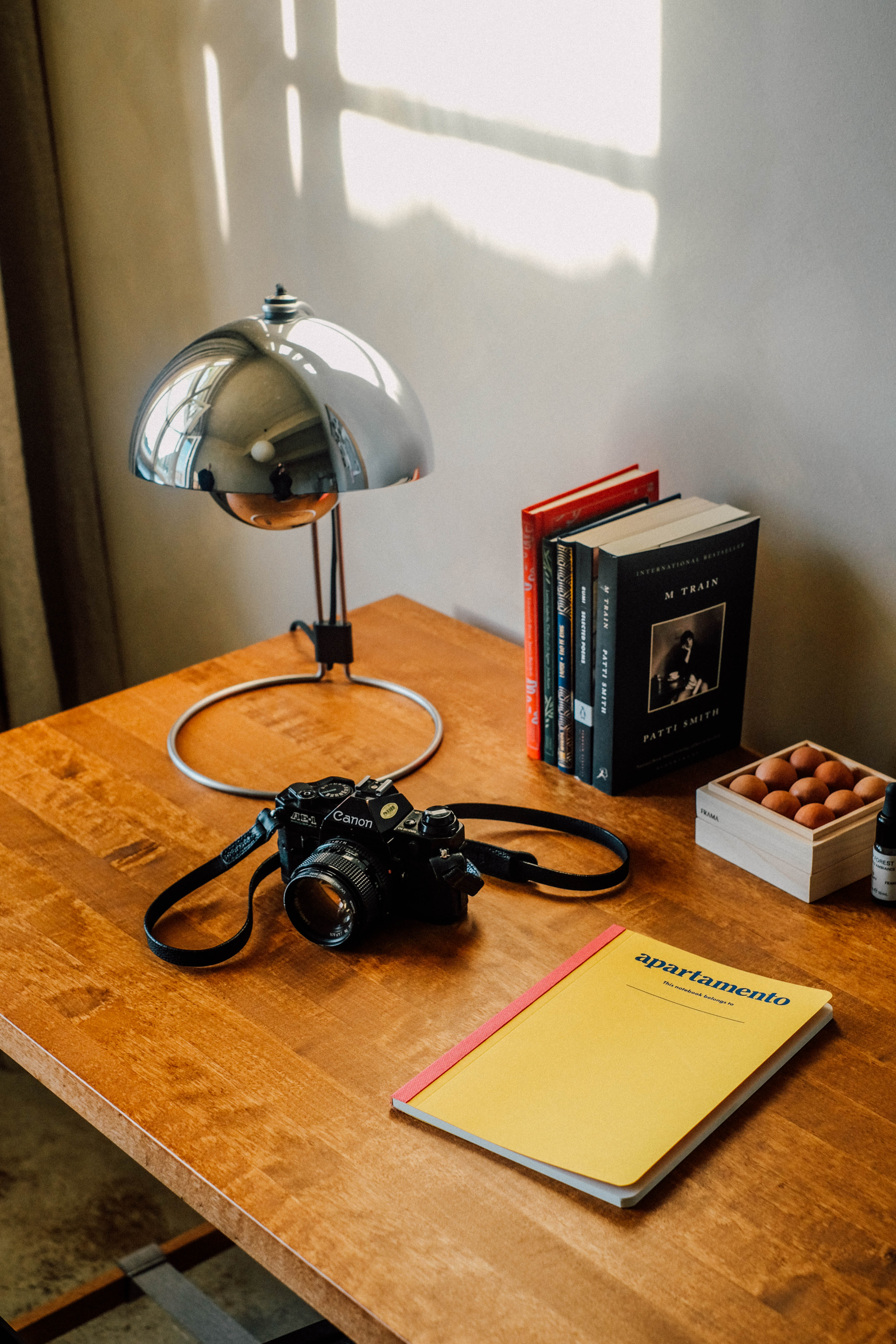 Een camera, lamp en boeken op een bureau.