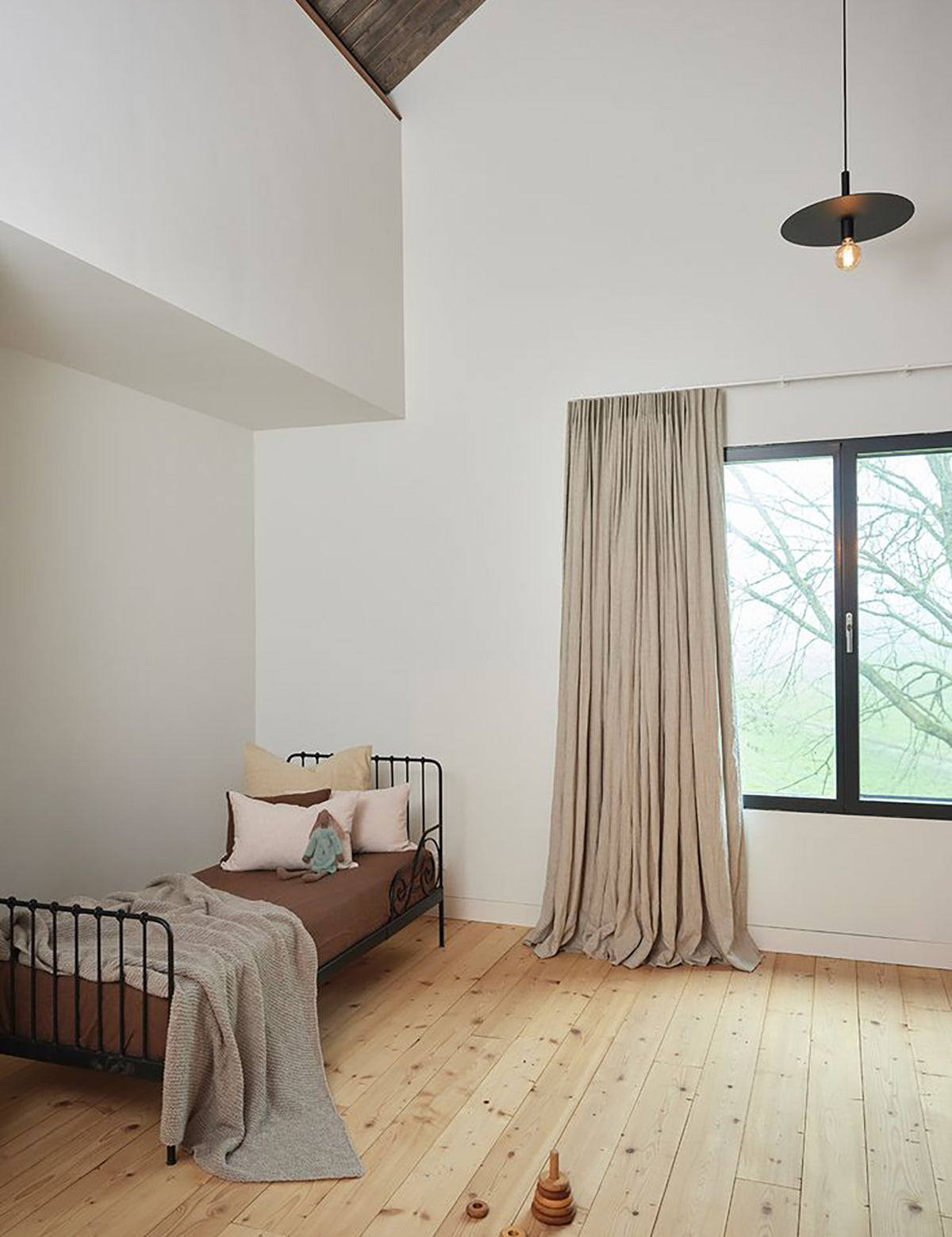 Kinderslaapkamer met bed, speelgoed en groot raam met By Mölle puur linnen gordijnen in flax.