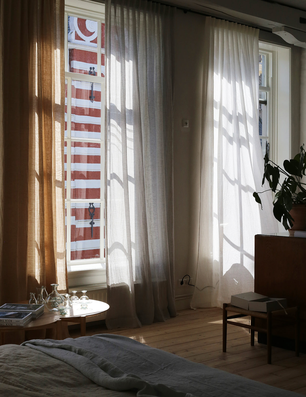 Slaapkamer met hoge ramen en inbetween linnen gordijnen van By Mölle.