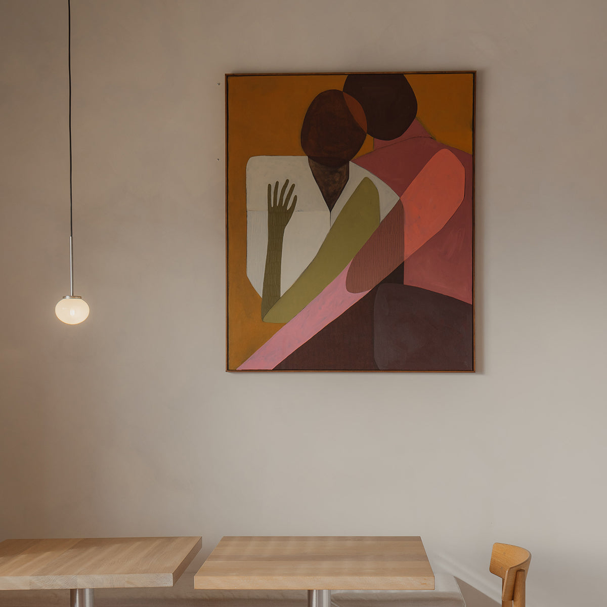Abstract painting on a wall above two wooden tables.