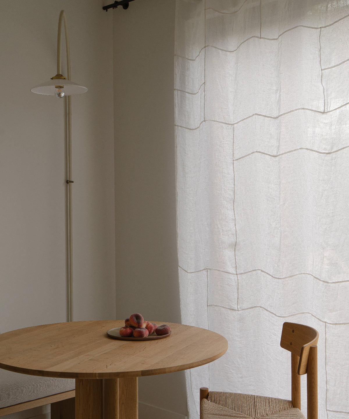 Eethoek met een houten tafel en stoelen, en een Pojagi patchwork gordijn paneel op de achtergrond.