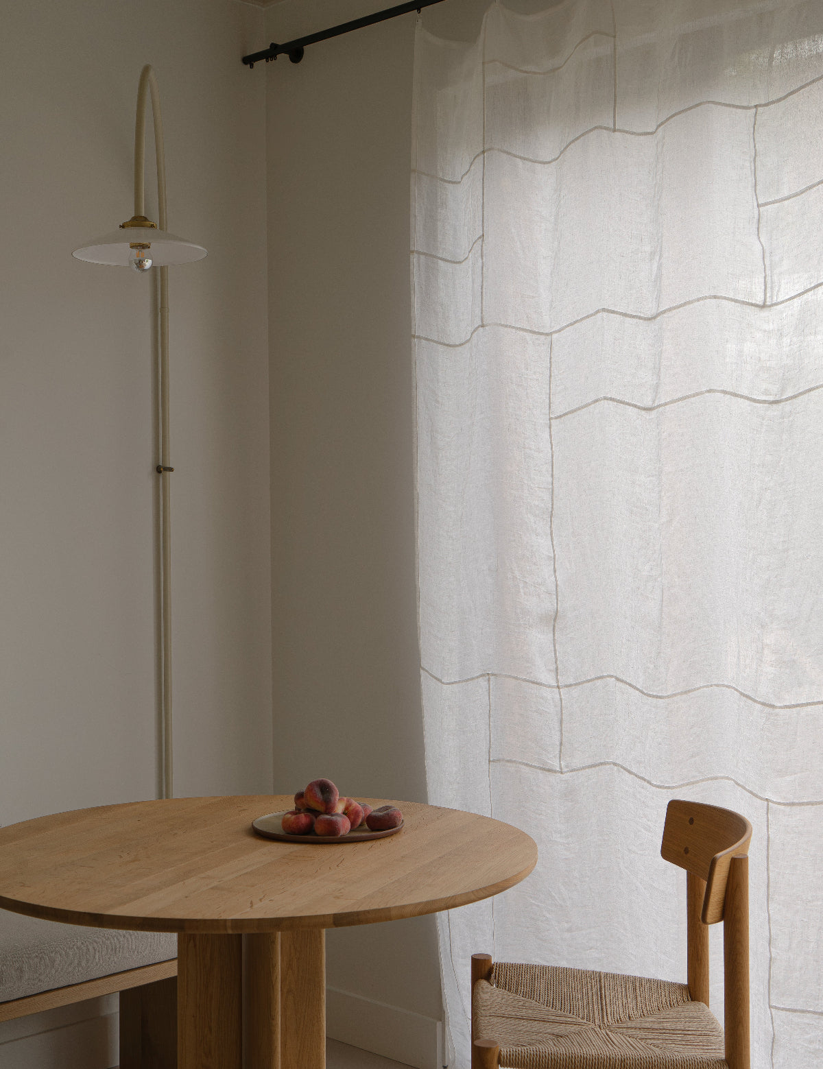 Eethoek met een houten tafel en stoelen, en een Pojagi patchwork gordijn paneel op de achtergrond.
