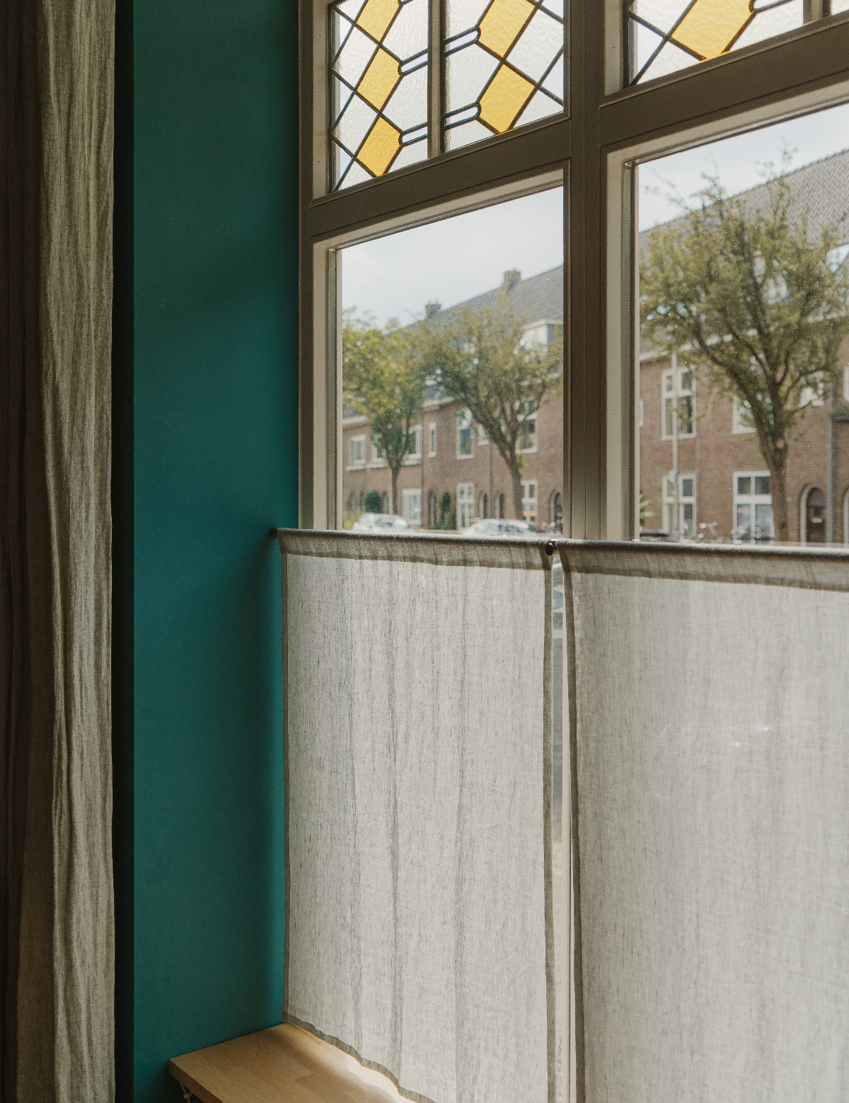 Raam met glas in lood en café curtains van in between linnen in de kleur fog.