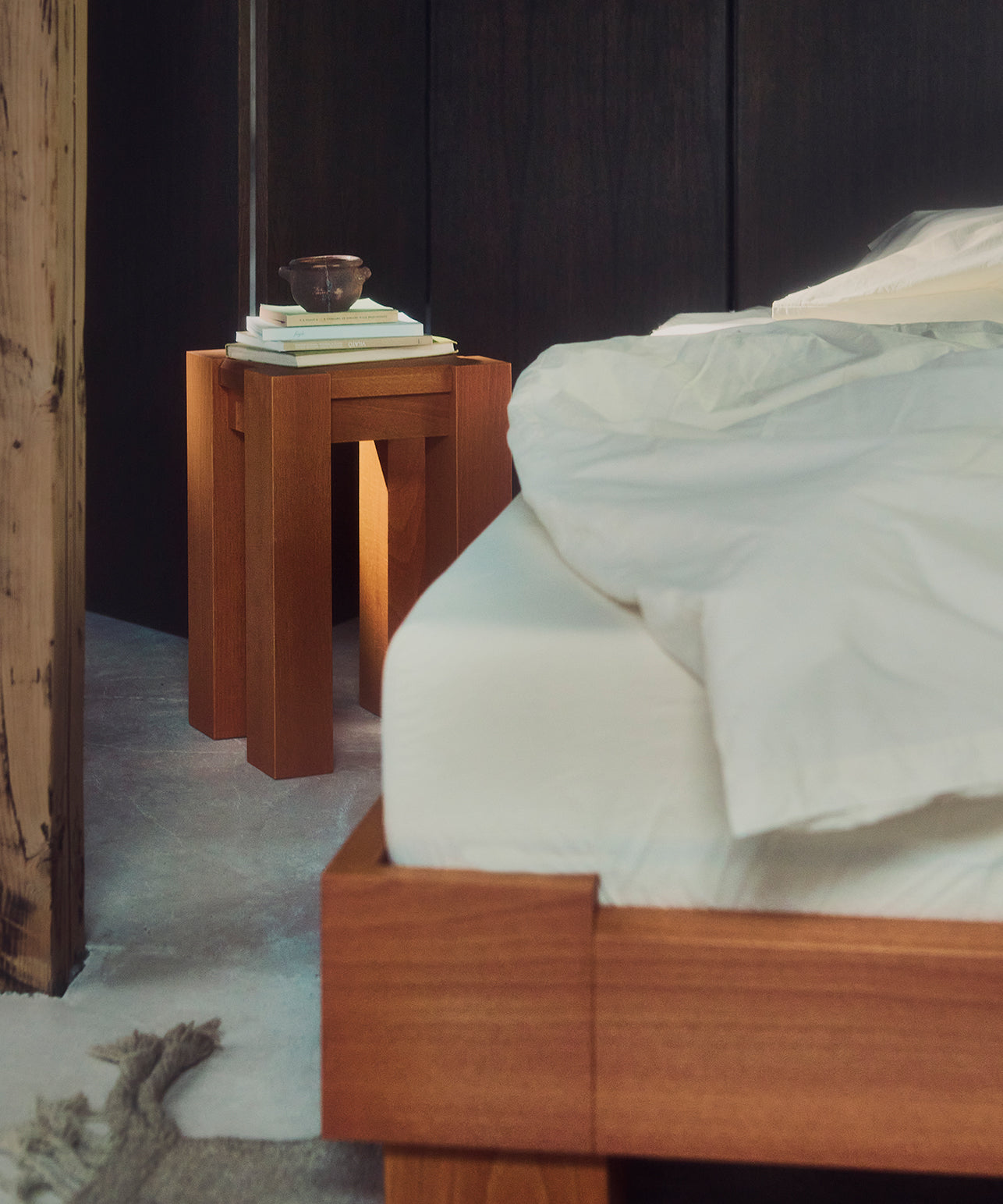 Houten bed Cubico en nachtkastjes in een slaapkamer met een donkere muur.
