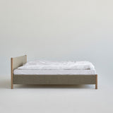 Minimalistisch houten bedframe, ontworpen door Rye Sleep en verkrijgbaar bij By Mölle. Met strakke Scandinavische lijnen, een laag silhouet en een zacht gestoffeerd hoofdbord combineert dit bed tijdloos design met natuurlijke materialen voor een rustige, moderne slaapkamer.