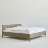 Minimalist wooden bed frame designed by Rye Sleep and available at By Mölle. Featuring clean Scandinavian lines, a low-profile form, and a softly upholstered headboard, this bed blends timeless design with natural materials for a calm, modern bedroom atmosphere