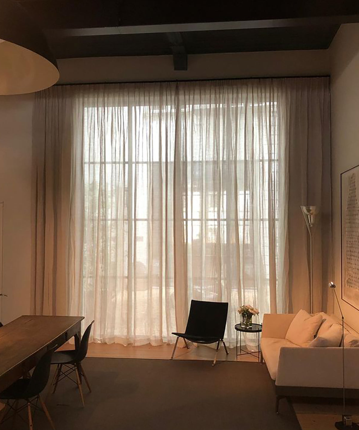 Moderne woonkamer met grote ramen en inbetween linnen gordijnen van By Mölle, die het licht zacht filteren.