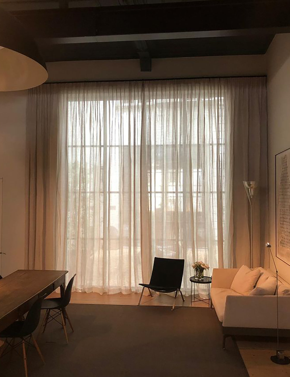 Moderne woonkamer met grote ramen en inbetween linnen gordijnen van By Mölle, die het licht zacht filteren.