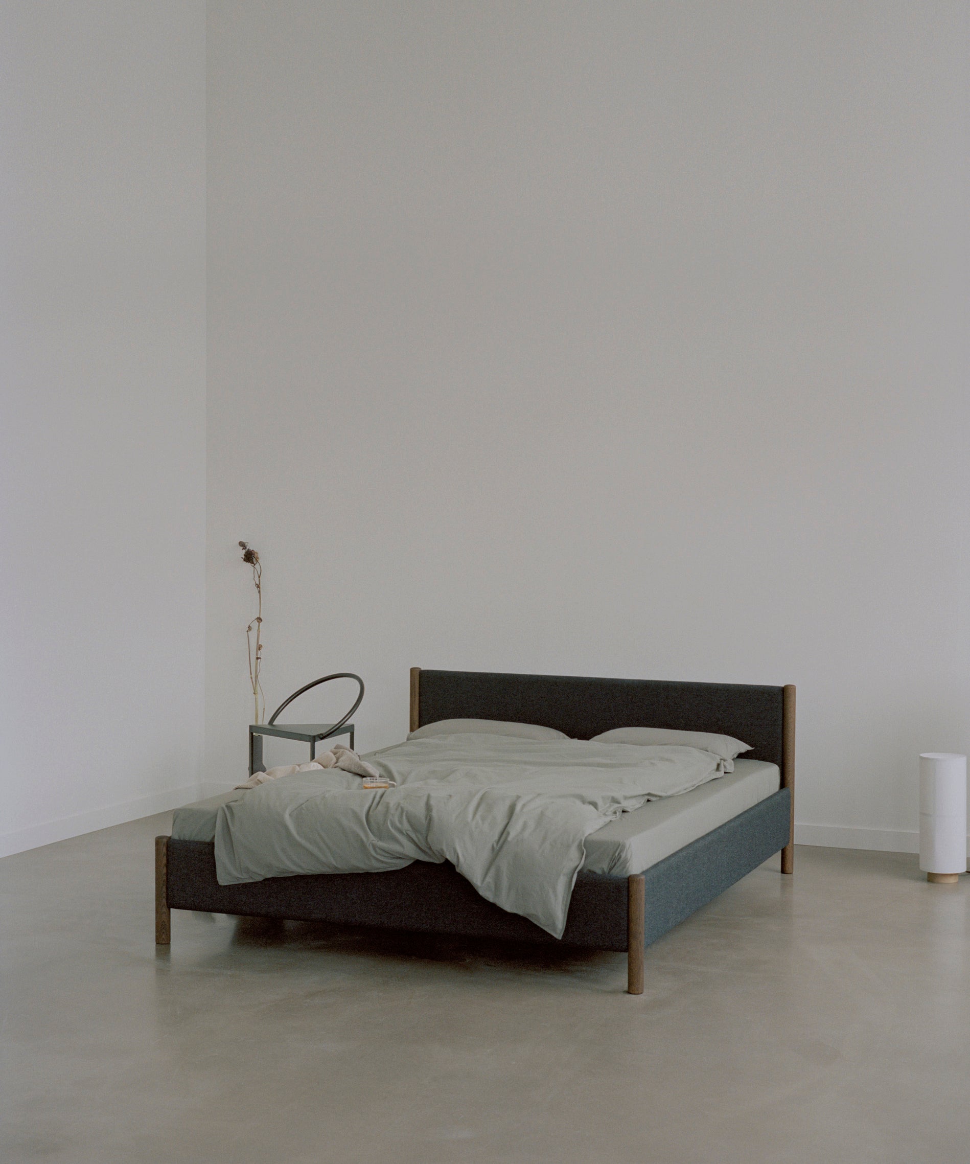 Bedframe van gerecycled wol en gerookt eiken in een donkere grijstint.