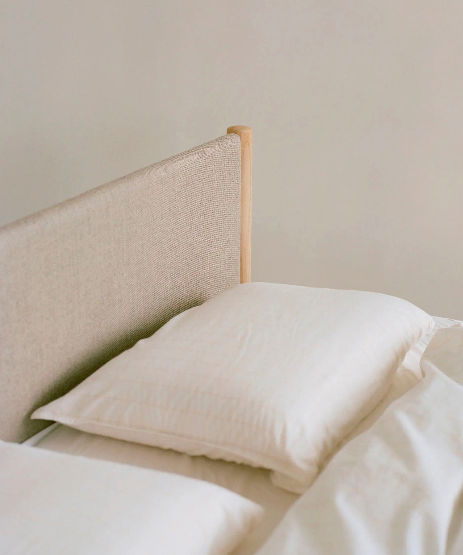 Beige gestoffeerd bed van gerecycled wol.